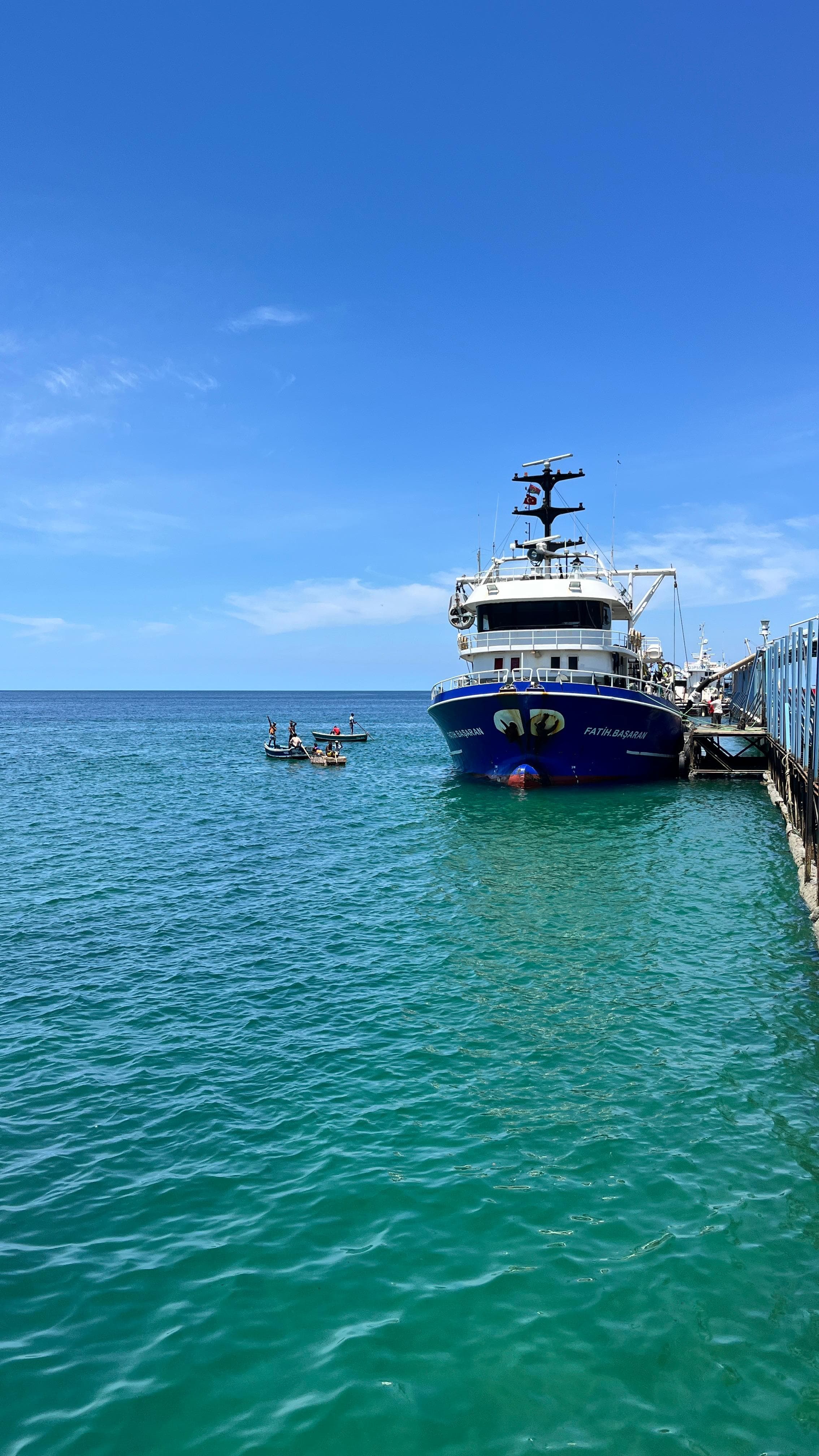 A vessel alongside the quay with small fishing boats offshore, on the Angolan coast